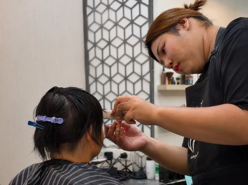 ช่างเฉพาะทางของ Wewigs Pro กำลังปรับทรงและเก็บแนวไรผมวิกผมแท้ให้ลูกค้าผู้ป่วยคีโมที่หน้าร้าน