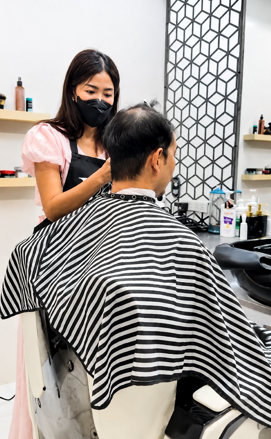คุณมน ผู้ก่อตั้งร้านวิกผม Wewigs Pro กำลังจัดวิกผมให้ลูกค้าผู้ชายที่มีปัญหาผมบางบริเวณกลางศีรษะ