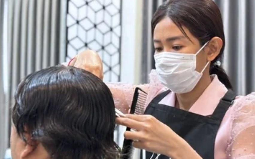 ช่างของร้านวิกผม Wewigs Pro กำลังใช้หวีและกรรไกรตัดแต่งทรงผมให้ลูกค้าที่หน้าร้าน
