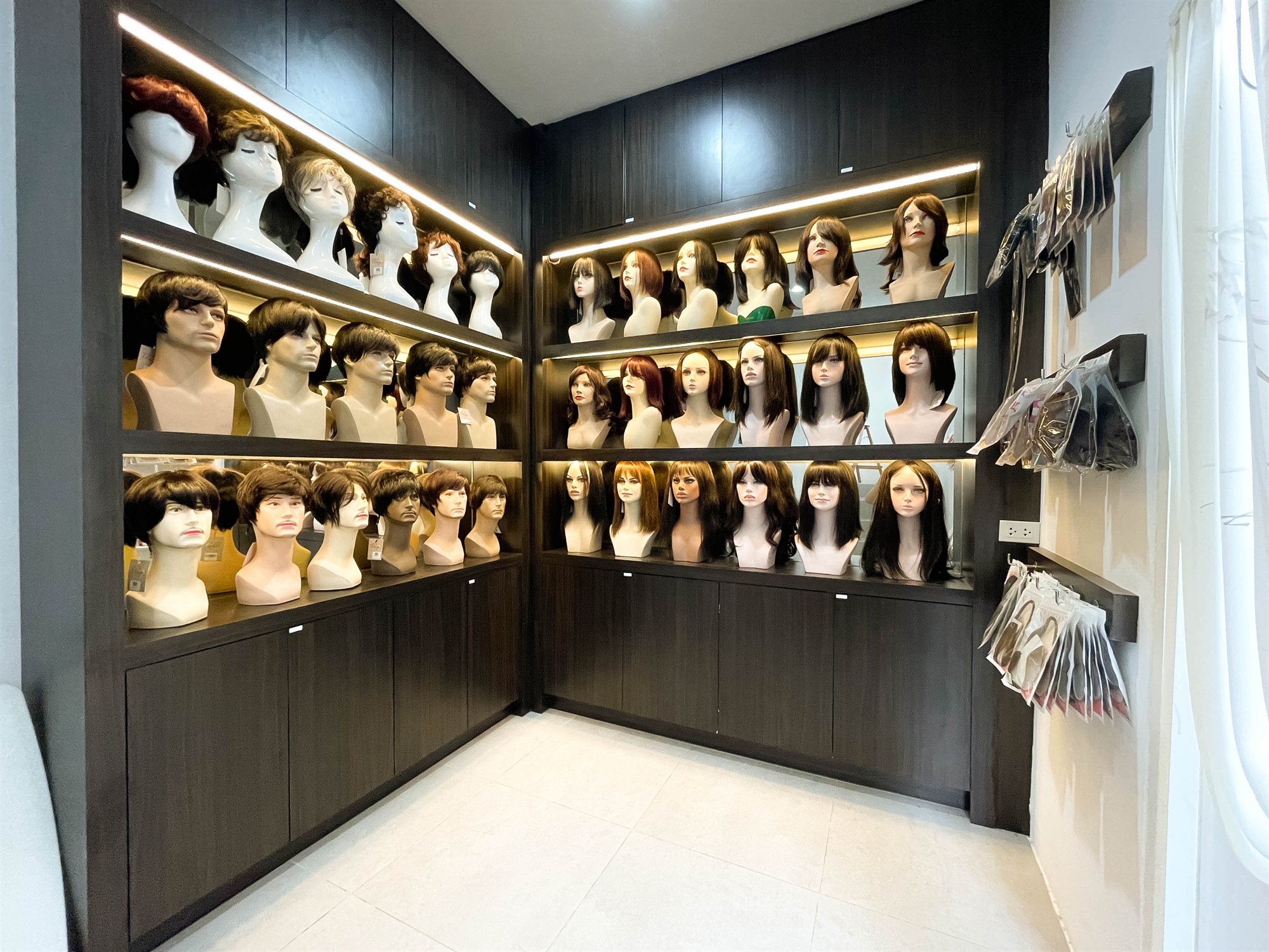 ห้องโชว์วิกผมแท้ที่ร้าน Wewigs Pro บางพลัด มีวิกผมชายและวิกผมหญิงหลายทรงเรียงบนชั้นไม้ ให้ผู้ป่วยเลือกดูของจริงก่อนตัดสินใจ